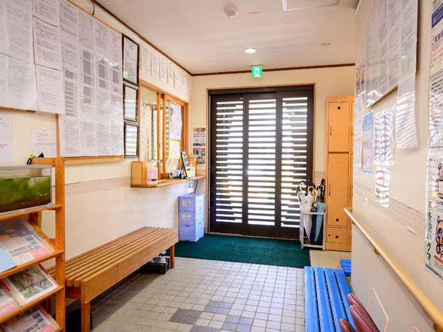 エントランスの明るい景色 情報豊富な掲示板が壁に並ぶ、開放的なエントランスです。待合いのベンチで、訪問者は快適な時間を過ごせます。