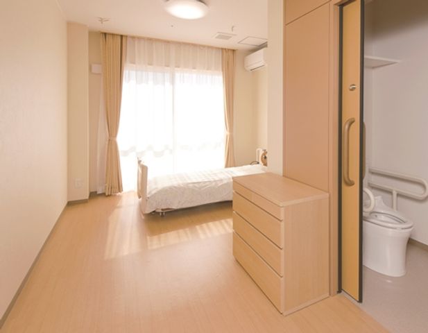 ベッドと自然光の居室 居室 広々とした居室は、木目調の落ち着いた雰囲気です。十分な自然光が入り、心地よく過ごせます。