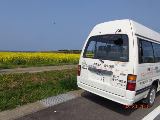 送迎車と菜の花畑の道  