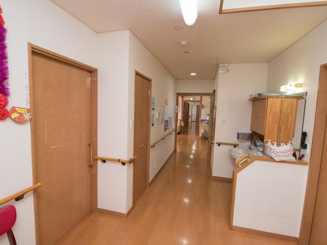 明るい廊下と手すり 通路 手すりが設置された廊下は、清潔感があり明るい印象を与えます。利用者が安心して過ごせる配慮が見受けられます。