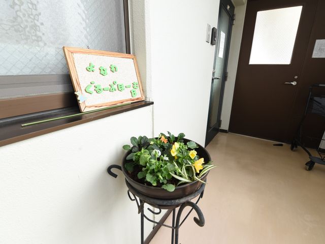 廊下の花と掲示物 玄関 廊下には、きれいな花と案内板が置かれ、温かみのある雰囲気を演出しています。ゆったりとしたスペースが確保されていて、快適にお過ごしいただける環境です。