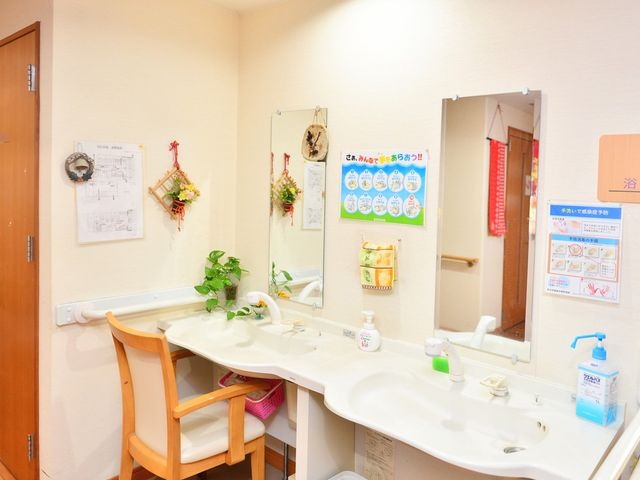 明るい洗面台 洗面台   広めの洗面スペースに、椅子付きの洗面台が並んでいます。手洗い案内も掲示され、清潔感のある環境です。