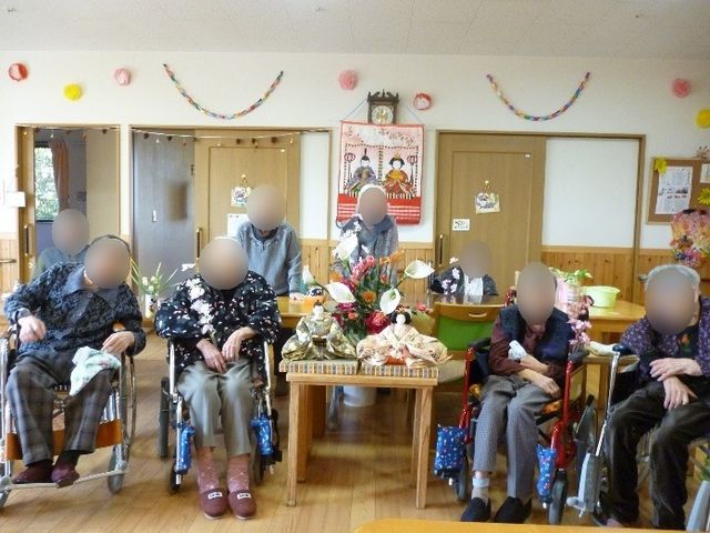 中央にテーブルのある食堂 イベント 中心には花の飾られたテーブルがあり、周囲には笑顔で集う人々の姿が見られる温かい雰囲気の食堂です。