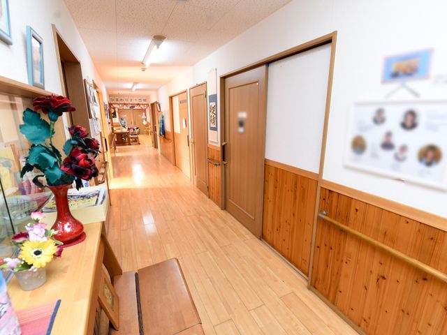 暖色の廊下と掲示物 廊下 木目調の壁が温もりを感じさせる廊下です。手すり沿いに歩けるため、安心して移動ができます。