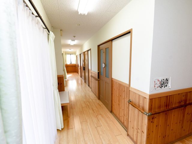 廊下の明るいイメージ 廊下 木目調の壁が温かみを感じさせる通路です。手すりも備えられ、安心して歩行できる設計となっております。