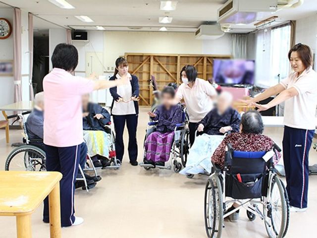 交流を楽しむ空間 多目的室 広々とした明るい空間で、車椅子の方々がスタッフと一緒に楽しむ様子が見られます。