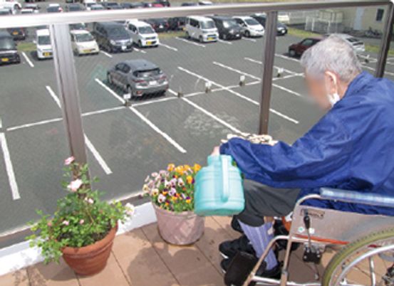 車椅子の人物と駐車場の景色のテラス  