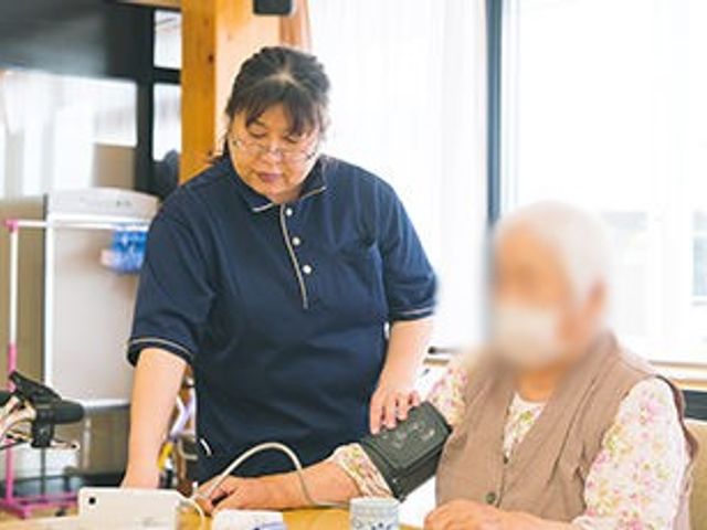 スタッフが介助中の部屋 居室 明るい空間で、スタッフが親切に対応しています。丁寧なサポートが期待できます。