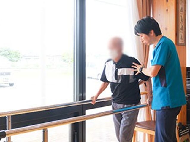 トレーニング光景 機能訓練室 窓からの光が差し込む場所で、スタッフがサポートしながらリハビリを行えます。