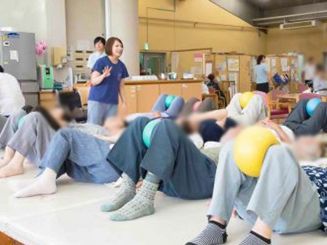 ボールを使う訓練中の様子 機能訓練室   リラックスした雰囲気で、スタッフと一緒にボールを使った運動が行われています。