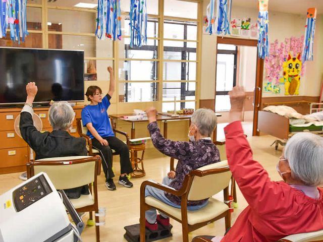 みんなで体操するラウンジ ラウンジ 自然光が差し込む明るい空間で、利用者の皆さんがリラックスしながら体操を楽しんでいます。