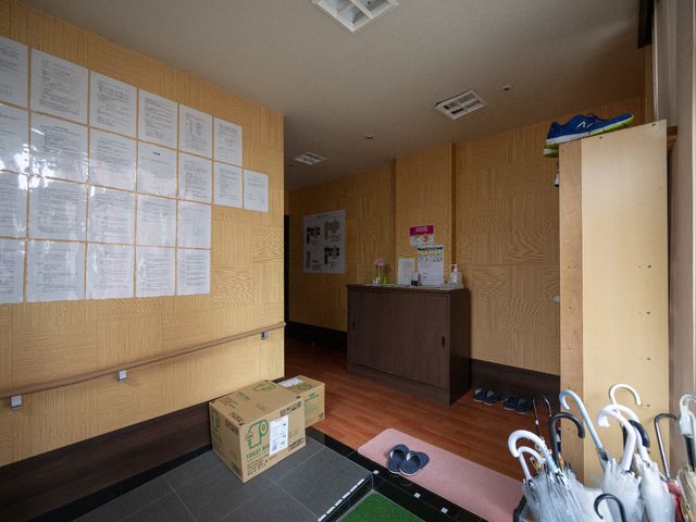 掲示物貼られた壁と受付 エントランス 多彩な情報が掲示された壁と整然と配置された受付が、日常の連携を支えています。必要な物品を常に整備し、安心の生活空間を提供しています。