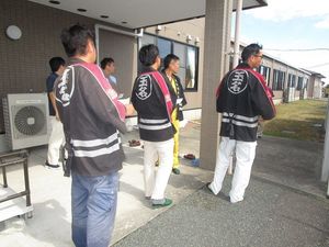 作業着の男性が並ぶ外観  