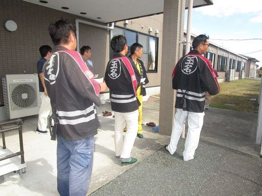 作業着の男性が並ぶ外観  
