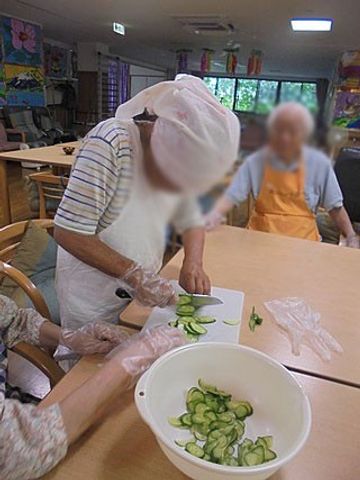 野菜を切る活動中の様子 ダイニングルーム 広々とした空間で、みなさんが楽しく料理を楽しんでいます。自然光が届く温かな雰囲気です。