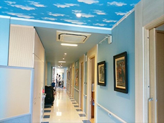 青空模様の廊下 廊下 天井に描かれた青空が印象的な廊下は、開放感のあふれる落ち着いた空間を提供しています。壁に飾られた絵画も訪れる方々に優しい癒しを与えています。
