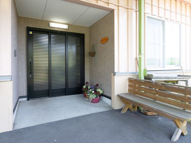 エントランスのベンチと花 外観 清潔感あるエントランスです。待合には木製のベンチと季節の花が迎えてくれます。