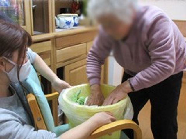 介護士のサポートシーン リビング スタッフが入居者をサポートする場面です。温かいコミュニケーションを通じて快適な日常を支えます。