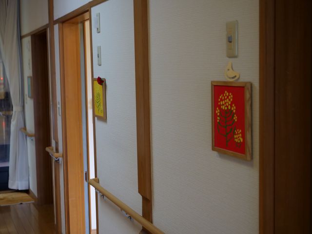 廊下の安心デザイン 廊下 手すりが備えられた落ち着いた色合いの廊下です。温かみのある壁掛けが心地よい雰囲気を演出しています。
