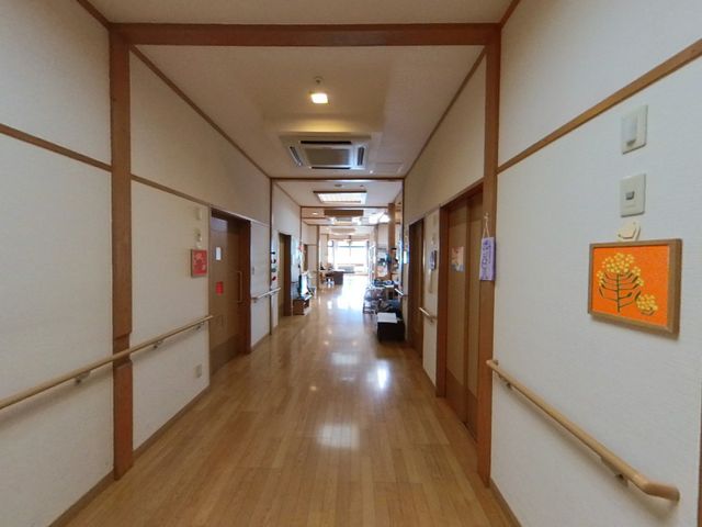 温もりある廊下 廊下 手すりが設けられた廊下は、光が差し込む温かみのある空間です。壁に掲示された絵も、日々の生活に彩りを与えています。