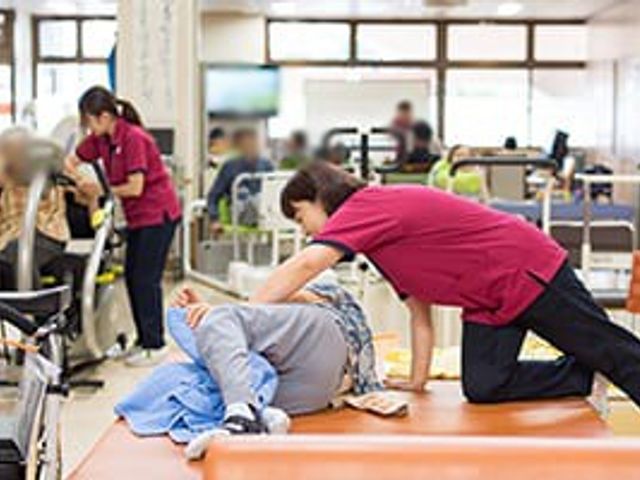 トレーニングの様子施設 機能訓練室 リハビリに従事するスタッフと利用者が、和やかな雰囲気の中で機能訓練をしています。