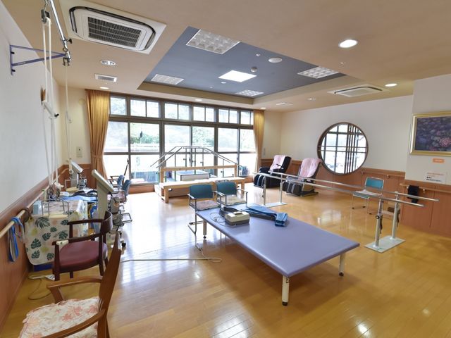 明るいリハビリテーションルーム 機能訓練室 広々とした窓から日差しの入る機能訓練室です。様々な訓練器具が整えられ、快適な環境で体力回復を支援します。