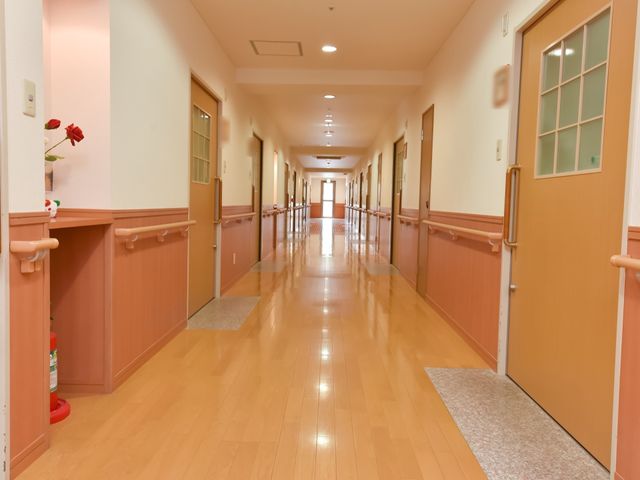 手すり付きの温かみのある廊下 廊下 優しい色合いで設計された廊下は、手すりが整備され安全に配慮されております。ゆったりとした空間でご利用者様の快適な移動をサポートします。