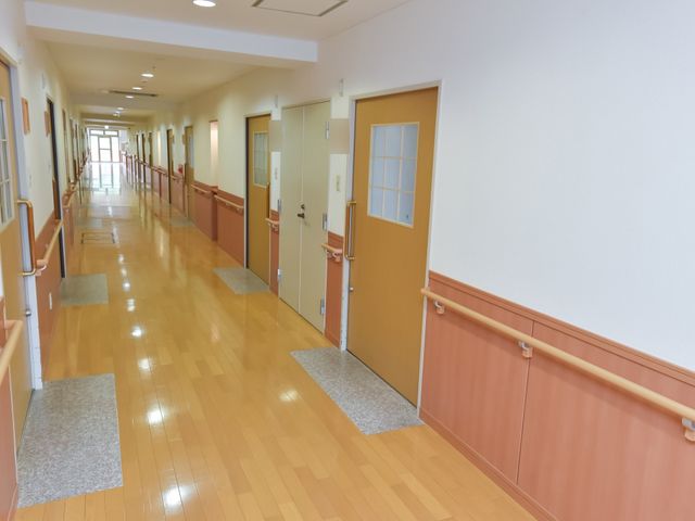 明るい廊下と部屋のドア 廊下 手すりが設置された、ゆったりとした廊下は、のびのびと安全に移動できる作りとなっております。