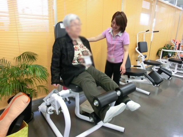 運動器具のある部屋 機能訓練室 明るい空間でスタッフが利用者をサポートしています。安心してトレーニングに取り組むことができます。