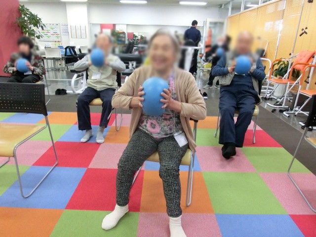 運動中の人々の部屋 機能訓練室 椅子に座りながらボールを使った運動を楽しめる部屋です。明るくカラフルな施設環境が魅力です。