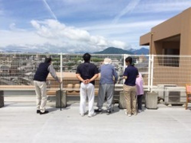 景色を眺める屋上 テラス 開放的な屋上で、利用者がスタッフと共に眺めを楽しんでいます。リフレッシュに最適な空間です。