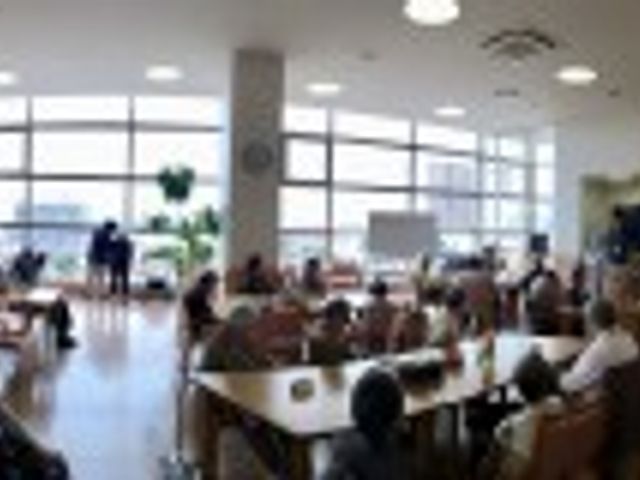 明るい共有スペース ラウンジ 広々とした明るい空間で、多くの人がくつろいでいます。自然光が差し込む快適なラウンジです。