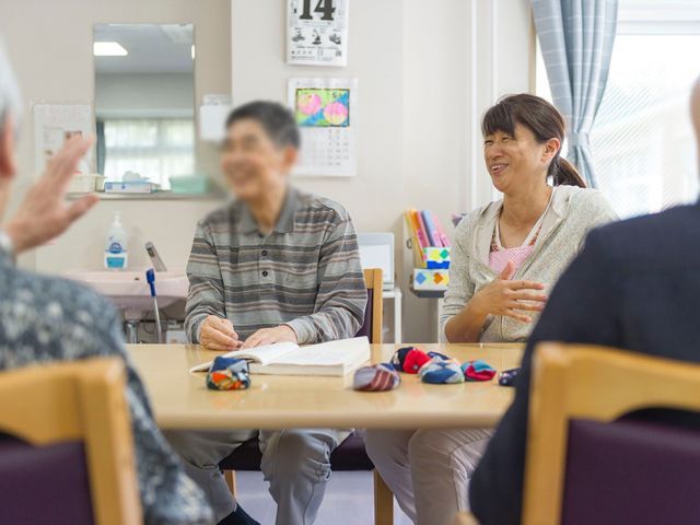 談話中のテーブル リビング 日差しが差し込む明るいリビングで、住人たちが和やかに会話を楽しんでいます。部屋全体がリラックスできる雰囲気です。