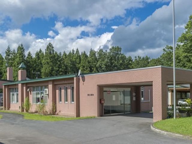 平屋の建物外観 外観   平屋づくりの落ち着いた建物で、正面に広い車寄せがあります。周囲の緑と青空が見え、明るい雰囲気です。