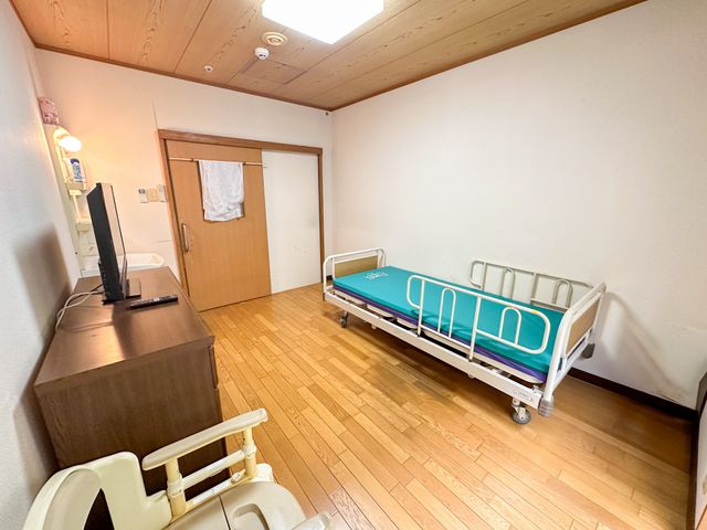 ベッドのある居室 居室 木製の床が広がる居室では、快適なベッドが設けられており、落ち着いた空間が演出されています。