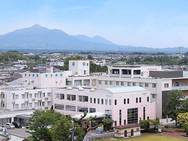 病院の外観 外観   山並みを望む開放的な立地で、建物全体が明るく見えます。働く場所として、周囲の景色も感じられる環境です。