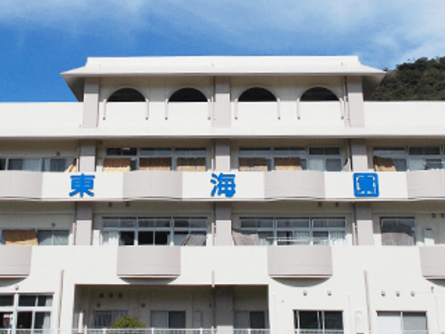 青い看板の建物正面 看板 明るい空の下にたたずむ建物の正面です。シンプルで目を引く青い看板が特徴的です。