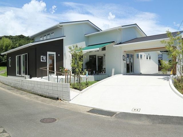 明るい建物の外観 外観   白と黒を基調にした建物で、広い駐車スペースが見えます。車での来訪や送迎もしやすそうなつくりです。