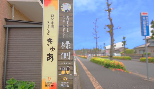 道沿いの看板 看板 訪問看護ステーションの看板が、道路沿いに設置されています。周囲は緑が豊かです。