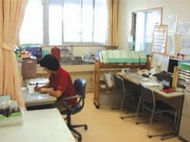 スタッフが働く事務室 スタッフイメージ 明るい空間で、スタッフが書類整理を行っています。快適な環境で業務が進められます。
