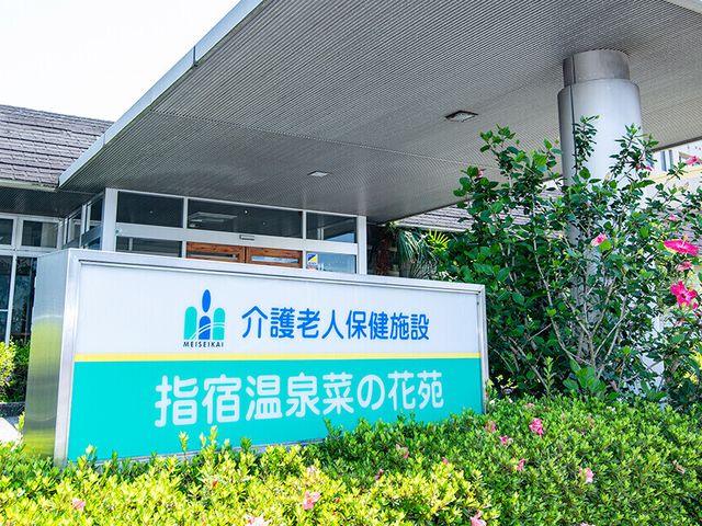 看板のある入口 看板 入口には施設の看板があり、周囲には緑が豊かです。施設の最初の印象を明るく演出しています。