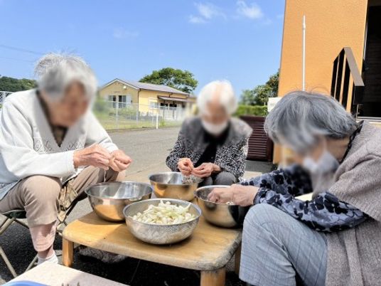 高齢者が野菜を剥いている庭