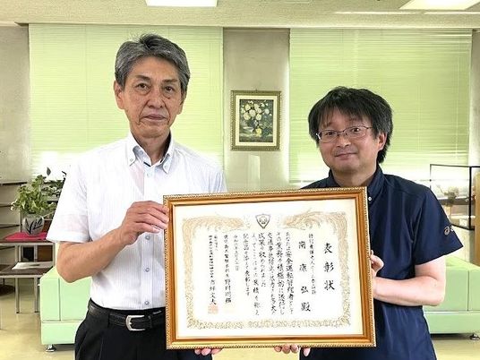 表彰状を持つ2人の室内  