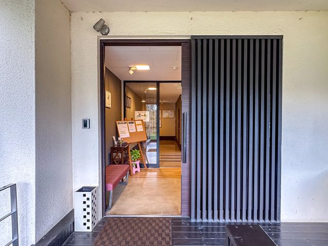 落ち着いた雰囲気の入口 エントランス 広い引き戸のエントランスは、快適で車椅子の出入りもスムーズです。掲示物も整然と配置されています。