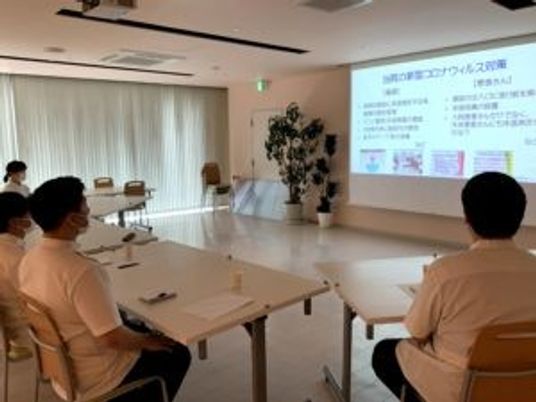 研修室で説明を聞く人々  