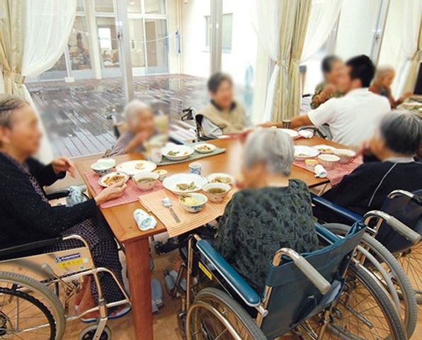交流を楽しむダイニング ダイニングルーム 車椅子にも対応したテーブルで、入居者の皆さんが食事を楽しんでいます。自然光が差し込む明るい環境です。