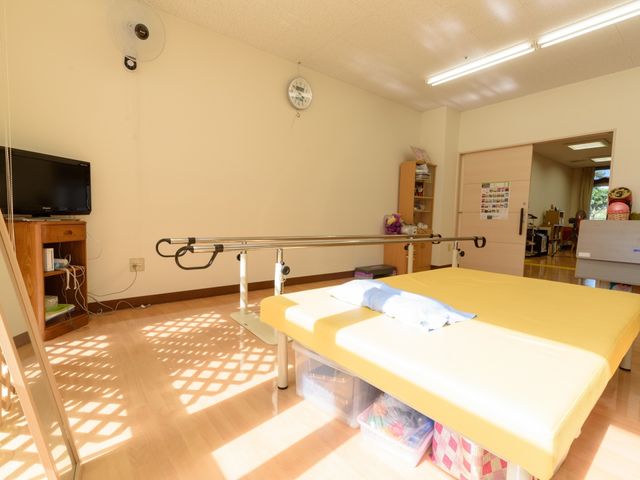 機能訓練用の広々とした部屋 機能訓練室 日差しの入る明るい機能訓練室です。リハビリ用のベッドが配置され、充実した環境でのサポートが可能です。