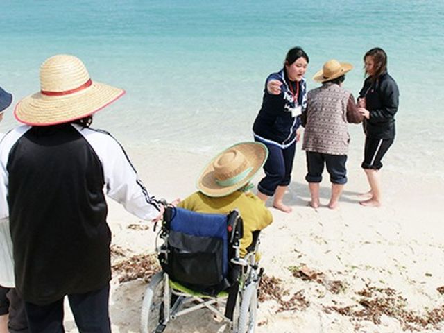 海辺の交流 中庭 穏やかな海辺で、利用者とスタッフが親しく交流しています。リラックスした雰囲気が魅力です。