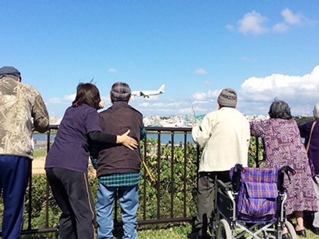 外の様子を楽しむ人々 庭 青い空の下で、利用者の方々が一緒にリラックスしています。人々の交流を感じられる場所です。