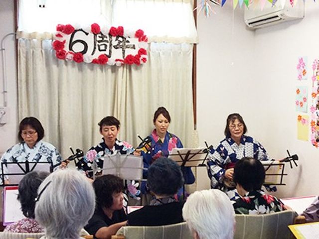 演奏会の様子 多目的室 利用者の皆さんが集まる演奏会が開かれています。和やかな雰囲気で、音楽を楽しんでいます。